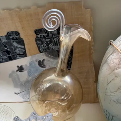 Vintage amber art glass decanter featuring a bulbous body, a slender neck with a flared spout, and a clear glass spiral handle.