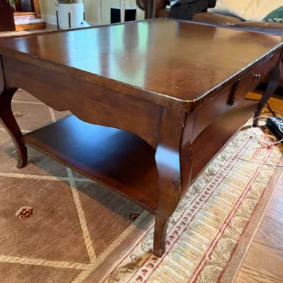 French Provincial style cherry wood coffee table featuring a lower storage shelf, cabriole legs, and a single drawer, showing some light...