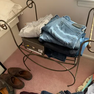 Sale Photo Thumbnail #130: A selection of men's clothing, including Levi's jeans and a Stokton shoe box, displayed on a decorative metal stand alongside leather shoes.