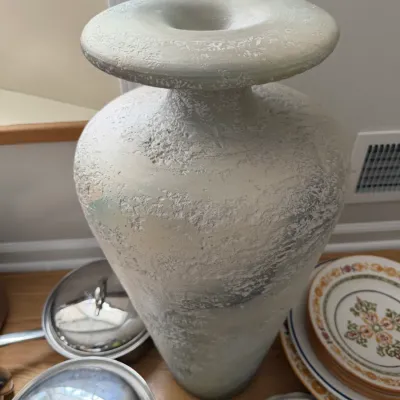 Large textured ceramic floor vase in a distressed off-white finish, shown alongside kitchenware and plates.
