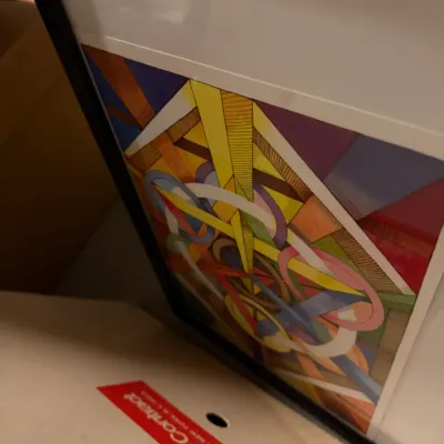 Sale Photo Thumbnail #230: Framed abstract geometric print featuring a vibrant composition of intersecting lines, circles, and colorful shapes, matted and housed in a black frame.