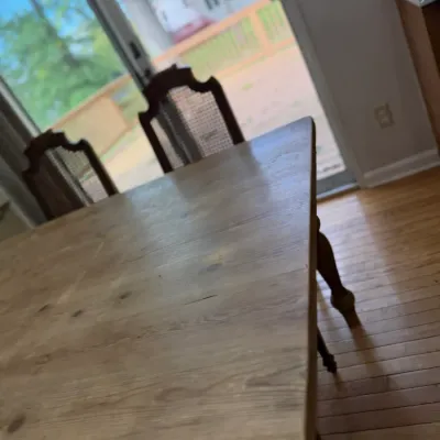 Vintage wood dining table with a natural finish, paired with high-back cane dining chairs.
