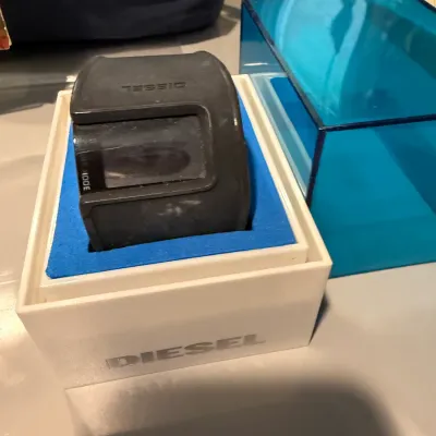 Sale Photo Thumbnail #157: Diesel digital watch with a black rubberized strap, presented in its original white and blue display box.
