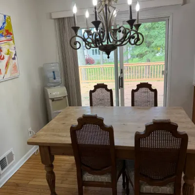 Rustic wooden dining table with turned legs, paired with four cane-back chairs featuring upholstered seats, illuminated by a classic...
