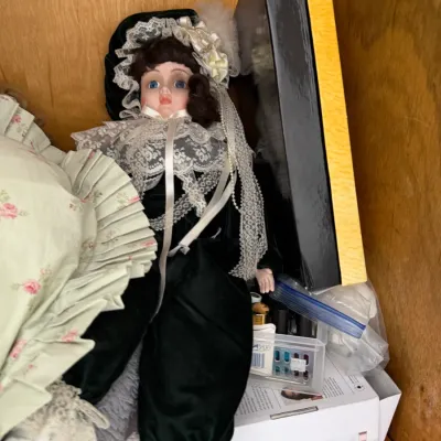 Sale Photo Thumbnail #138: Vintage porcelain collector doll dressed in a black velvet and lace outfit, displayed on a wooden shelf.