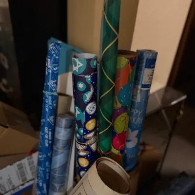 Sale Photo Thumbnail #169: Assorted rolls of holiday wrapping paper, including Hanukkah-themed designs and colorful patterns.