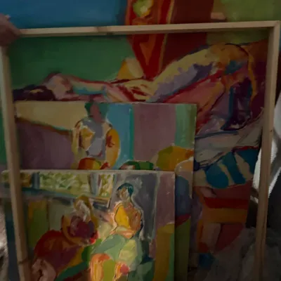 Sale Photo Thumbnail #206: Collection of colorful, abstract expressionist oil paintings depicting figures and landscapes, stacked in simple wooden frames.