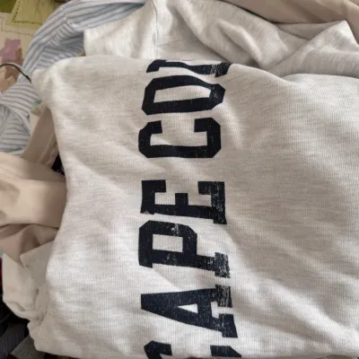 Sale Photo Thumbnail #113: Light gray Cape Cod sweatshirt in size XL, shown folded among other clothing items.