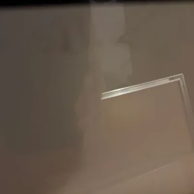 Sale Photo Thumbnail #227: A blurry, out-of-focus photograph showing a reflective surface, possibly a television screen or glass frame, in a dimly lit room.