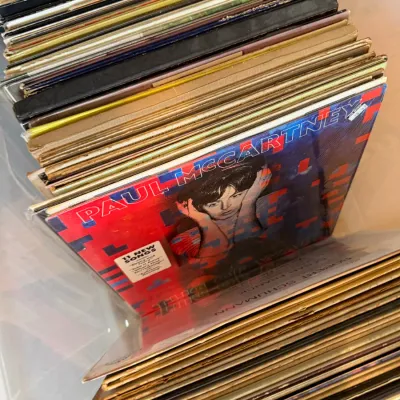 Collection of vintage vinyl records stored in a plastic bin, featuring Paul McCartney's "Tug of War" album from 1982.