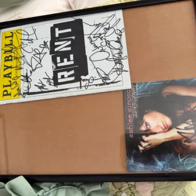 Sale Photo Thumbnail #111: Framed memorabilia featuring a signed Playbill from the Broadway musical Rent and a signed Ashlee Simpson Autobiography CD booklet.