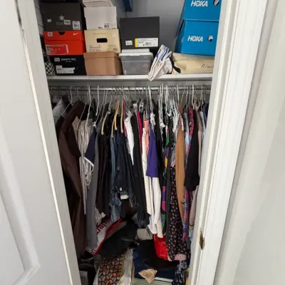 Sale Photo Thumbnail #143: Closet filled with hanging clothing, including jackets and shirts, with various shoe boxes from brands like Hoka, Nike, and Kenneth Cole stacked on the top shelf.