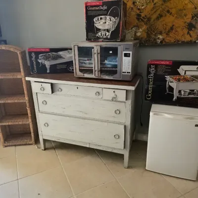 Distressed white painted wooden dresser with an Oster toaster oven, boxed Gourmet Buffet chafing dishes, a small white Magic Chef...