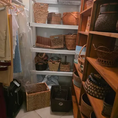 Large collection of woven wicker, rattan, and wood baskets in various shapes and sizes, displayed on metal and wooden shelving units.