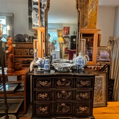 Drexel Heritage Chinoiserie-style black lacquered chest of drawers with gold-painted scenes, paired with a matching arched wall mirror...