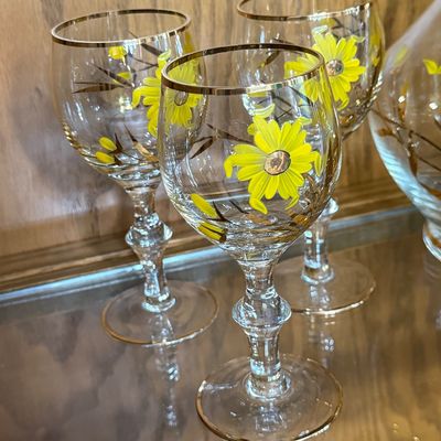 Sale Photo Thumbnail #72: A beautiful mid-century vintage glassware set featuring a hand-painted yellow daisy and gold leaf design with gold-gilded rims. This 7-piece set includes one handled decanter pitcher, a matching glass stopper with a frosted ground base, and six coordinati