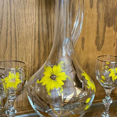 Sale Photo Thumbnail #73: A beautiful mid-century vintage glassware set featuring a hand-painted yellow daisy and gold leaf design with gold-gilded rims. This 7-piece set includes one handled decanter pitcher, a matching glass stopper with a frosted ground base, and six coordinati