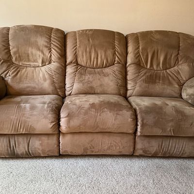 Sale Photo Thumbnail #93: A comfortable three-seat reclining sofa by La-Z-Boy. Features plush microfiber upholstery in a neutral tan/brown tone. The two outer seats feature manual reclining mechanisms operated by side levers. Does show some typical shading variations in the microf