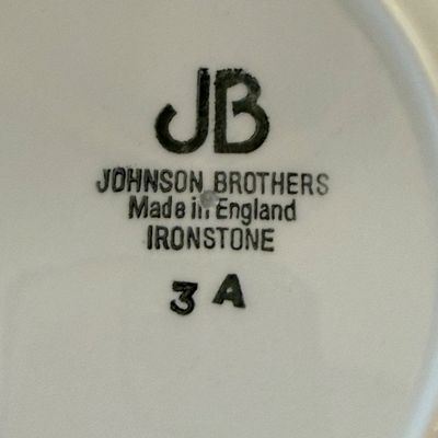 Sale Photo Thumbnail #89: A mixed ceramic set featuring four tea cups marked "Made in China" and a collection of matching saucers and side plates. The side plates are marked "JB Johnson Brothers Made in England Ironstone 3 A". All pieces feature a matching pink and white rose flor