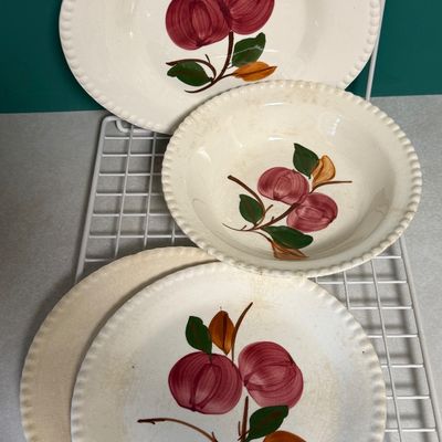 Sale Photo Thumbnail #91: A vintage set of hand-painted ceramic dinnerware by Blue Ridge Southern Potteries, Inc. featuring a classic red apple and green leaf motif with a beaded rim design. The set includes two plates, one bowl, and one additional plate/saucer base. The underside