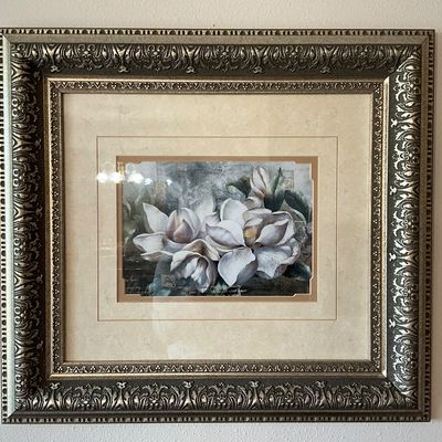 Sale Photo Thumbnail #97: A beautiful framed art print featuring white magnolia blossoms. The print is set within a multi-layered matting and housed in an ornate, metallic-finished composite frame with detailed scrollwork. Protected under glass. Excellent condition with no visible