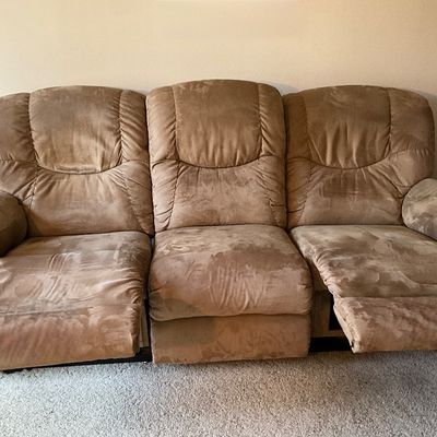 Sale Photo Thumbnail #94: A comfortable three-seat reclining sofa by La-Z-Boy. Features plush microfiber upholstery in a neutral tan/brown tone. The two outer seats feature manual reclining mechanisms operated by side levers. Does show some typical shading variations in the microf