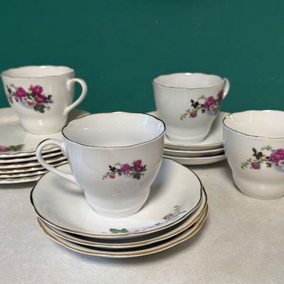 Sale Photo Thumbnail #86: A mixed ceramic set featuring four tea cups marked "Made in China" and a collection of matching saucers and side plates. The side plates are marked "JB Johnson Brothers Made in England Ironstone 3 A". All pieces feature a matching pink and white rose flor