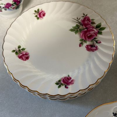 Sale Photo Thumbnail #90: A mixed ceramic set featuring four tea cups marked "Made in China" and a collection of matching saucers and side plates. The side plates are marked "JB Johnson Brothers Made in England Ironstone 3 A". All pieces feature a matching pink and white rose flor