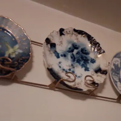 Sale Photo Thumbnail #68: Trio of vintage blue and white decorative porcelain plates displayed on a wall-mounted wire rack.