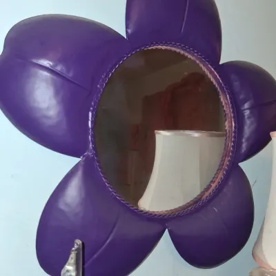Sale Photo Thumbnail #41: Whimsical purple flower-shaped wall mirror with metal frame and braided trim around the circular glass.