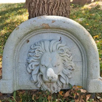 Sale Photo Thumbnail #3: Vintage cast stone lion head wall fountain plaque with a weathered, distressed finish, showing some chipping and cracking consistent with outdoor age.