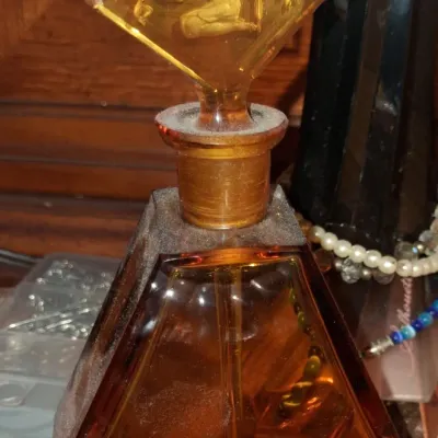 Sale Photo Thumbnail #34: Art Deco amber glass perfume bottle featuring a hexagonal body and a matching stopper with a molded relief of a female figure.
