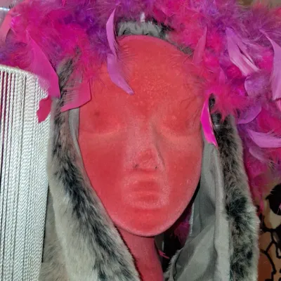 Sale Photo Thumbnail #23: Faux fur trapper hat with ear flaps, topped with a vibrant pink and purple feather boa, displayed on a red mannequin head.