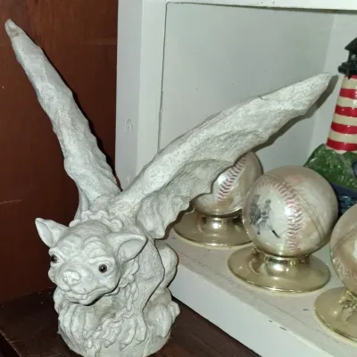 Sale Photo Thumbnail #17: Gothic-style cast stone gargoyle figurine with outstretched wings, shown alongside decorative baseball globes on a shelf.