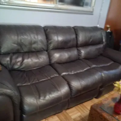 Sale Photo Thumbnail #146: Dark brown leather reclining sofa with plush, segmented back cushions and padded armrests.