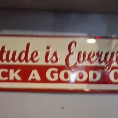 Sale Photo Thumbnail #92: Embossed metal sign featuring the motivational phrase "Attitude is Everything PICK A GOOD ONE" in red and cream lettering.