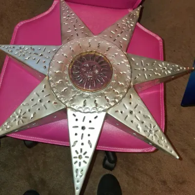 Sale Photo Thumbnail #26: Mexican punched tin star lantern featuring a central glass sun face medallion, showing some light surface wear.