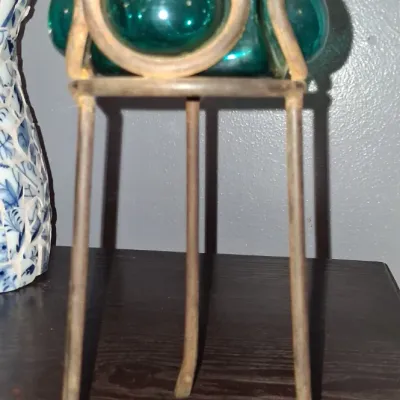 Sale Photo Thumbnail #117: Vintage teal blown glass votive holder set in a rustic three-legged metal stand.