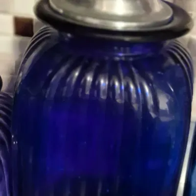 Sale Photo Thumbnail #77: Vintage cobalt blue ribbed glass canister featuring a brushed metal lid with a ball finial.