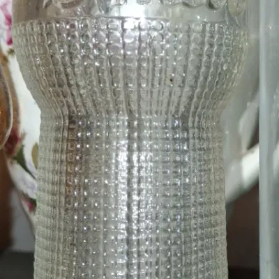 Sale Photo Thumbnail #59: Vintage clear glass Smile soda bottle featuring a textured hobnail-style pattern and embossed script lettering.