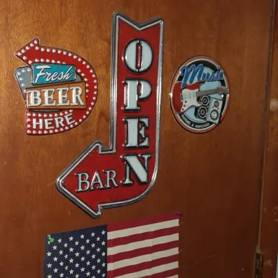Sale Photo Thumbnail #58: Collection of novelty bar signs and decor, including a retro-style "Open Bar" arrow sign, a "Fresh Beer Here" sign, an Uncle Sam pointing hand graphic, and a small American flag.