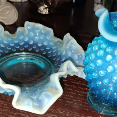 Sale Photo Thumbnail #132: Fenton blue opalescent hobnail glass set, including a ruffled edge bowl and a matching small vase, circa mid-20th century.