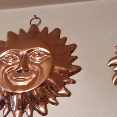 Sale Photo Thumbnail #81: Trio of vintage copper sun face wall hangings in graduated sizes, featuring stylized celestial designs with hanging loops.