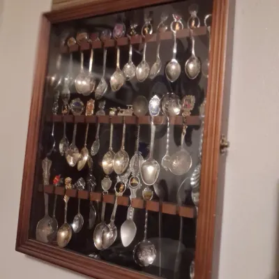 Sale Photo Thumbnail #72: Vintage wooden wall-mounted display case filled with a collection of collectible souvenir spoons.