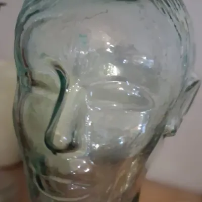 Sale Photo Thumbnail #91: Vintage light green glass mannequin head, commonly used for displaying hats or headphones, in good condition.
