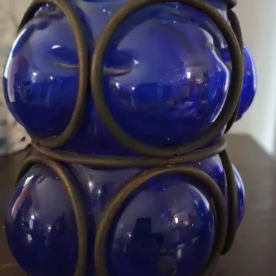 Sale Photo Thumbnail #110: Vintage cobalt blue blown glass votive holder encased in a rustic metal wire frame.