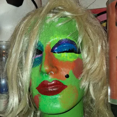 Sale Photo Thumbnail #20: Hand-painted styrofoam mannequin head featuring a vibrant green face, colorful makeup details, and a blonde wig.