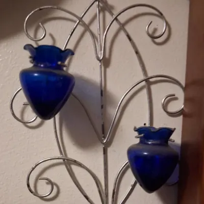 Sale Photo Thumbnail #70: Vintage silver-tone wire wall sconce featuring scrollwork details and two cobalt blue glass votive holders.
