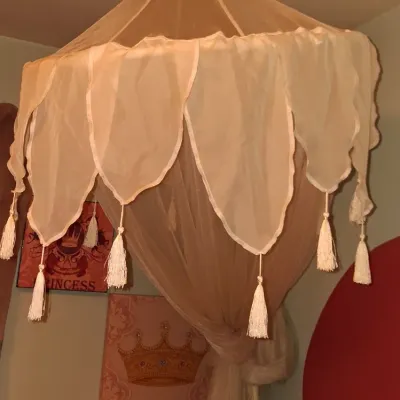 Sale Photo Thumbnail #47: Sheer cream-colored bed canopy featuring scalloped edges and hanging tassels, suspended from a ceiling hook.