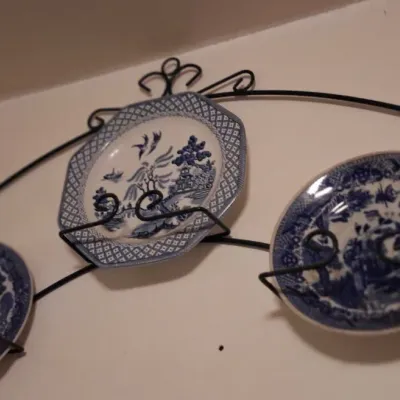Sale Photo Thumbnail #67: Three vintage blue and white transferware plates, including a Blue Willow pattern, displayed on a black wrought iron wall hanger.